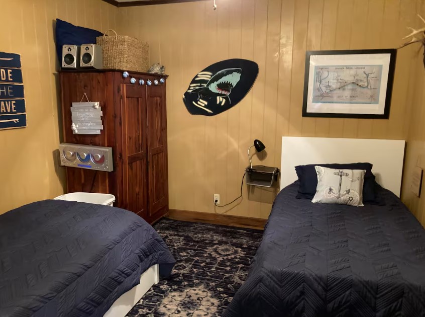 bedroom with twin beds, brown walls, brown cabinet