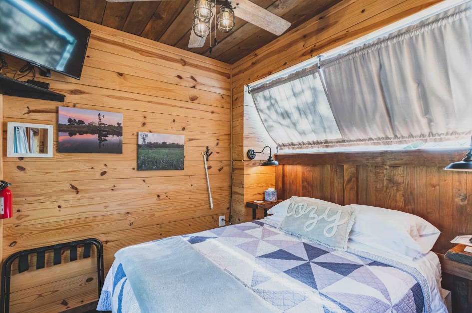 bedroom with a bed, wooden walls, mounted flat screen tv