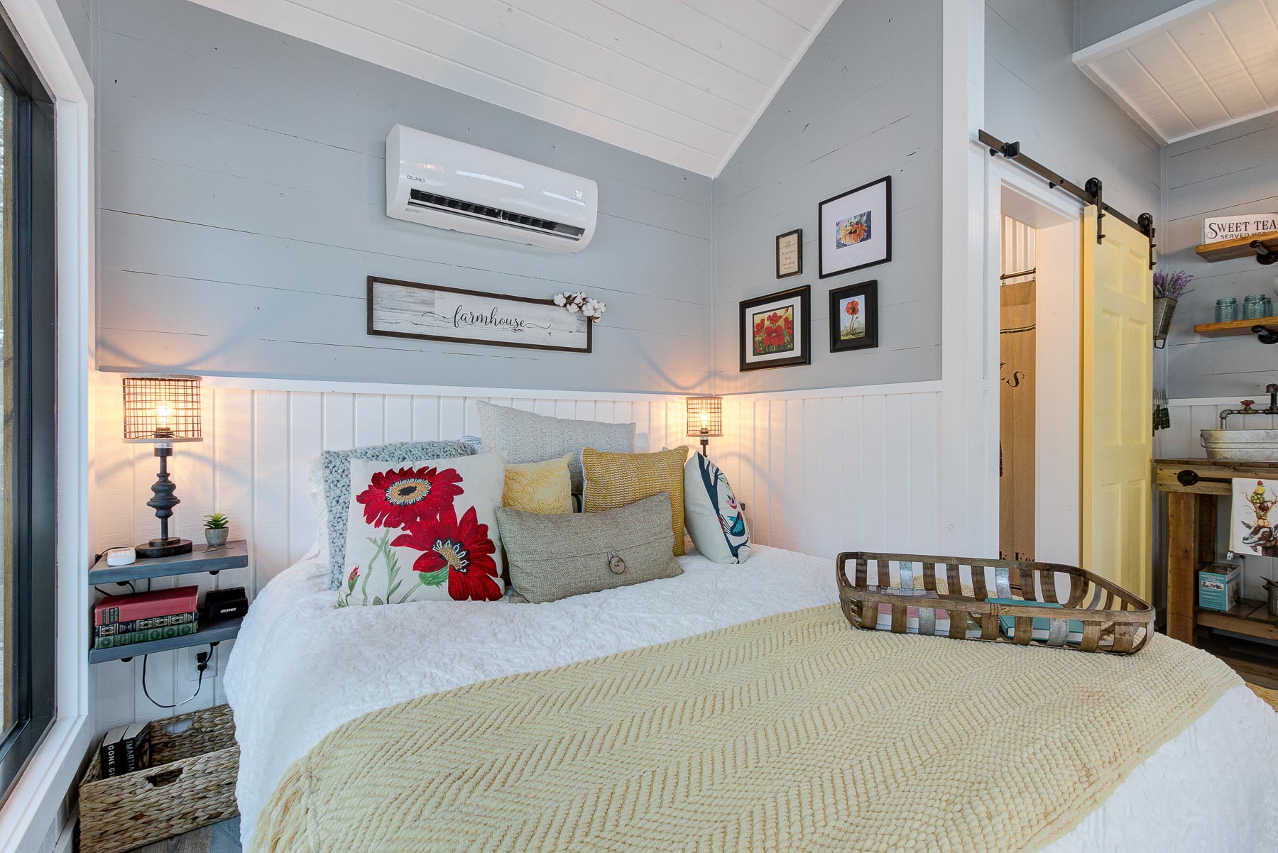 bedroom with a bed, bedside table, white ac, framed photos