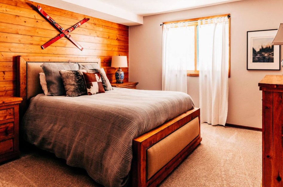 bedroom with light curtains on the window, wooden accent wall, comfy bed