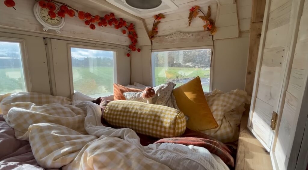 bedroom surrounded by windows and a lot of blankets and soft pillows