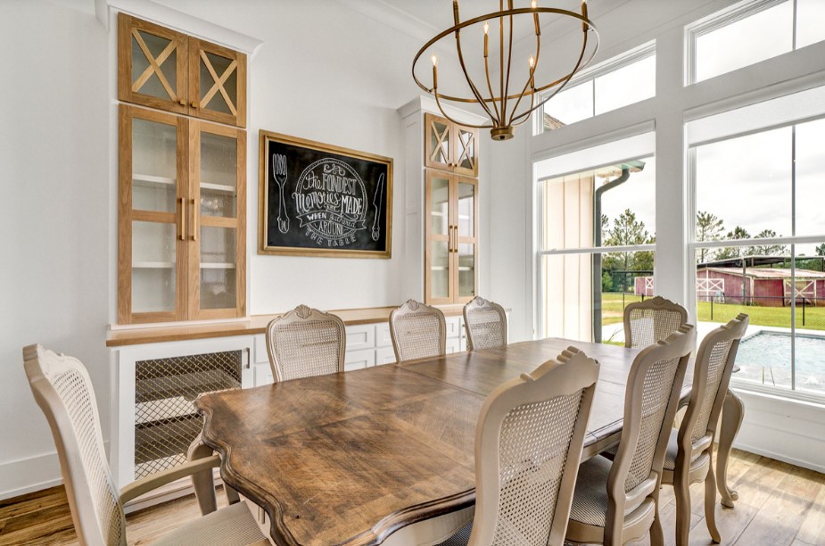 dining room with a brown dining table, white cabinets, large windows