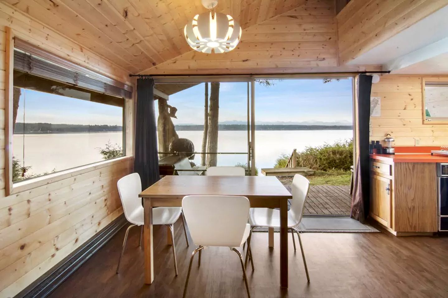 dining room with a brown table, white chairs, glass doors and a big window