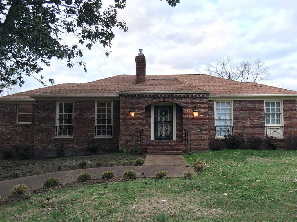 exterior of a home with dark red bricks and tiny bushes