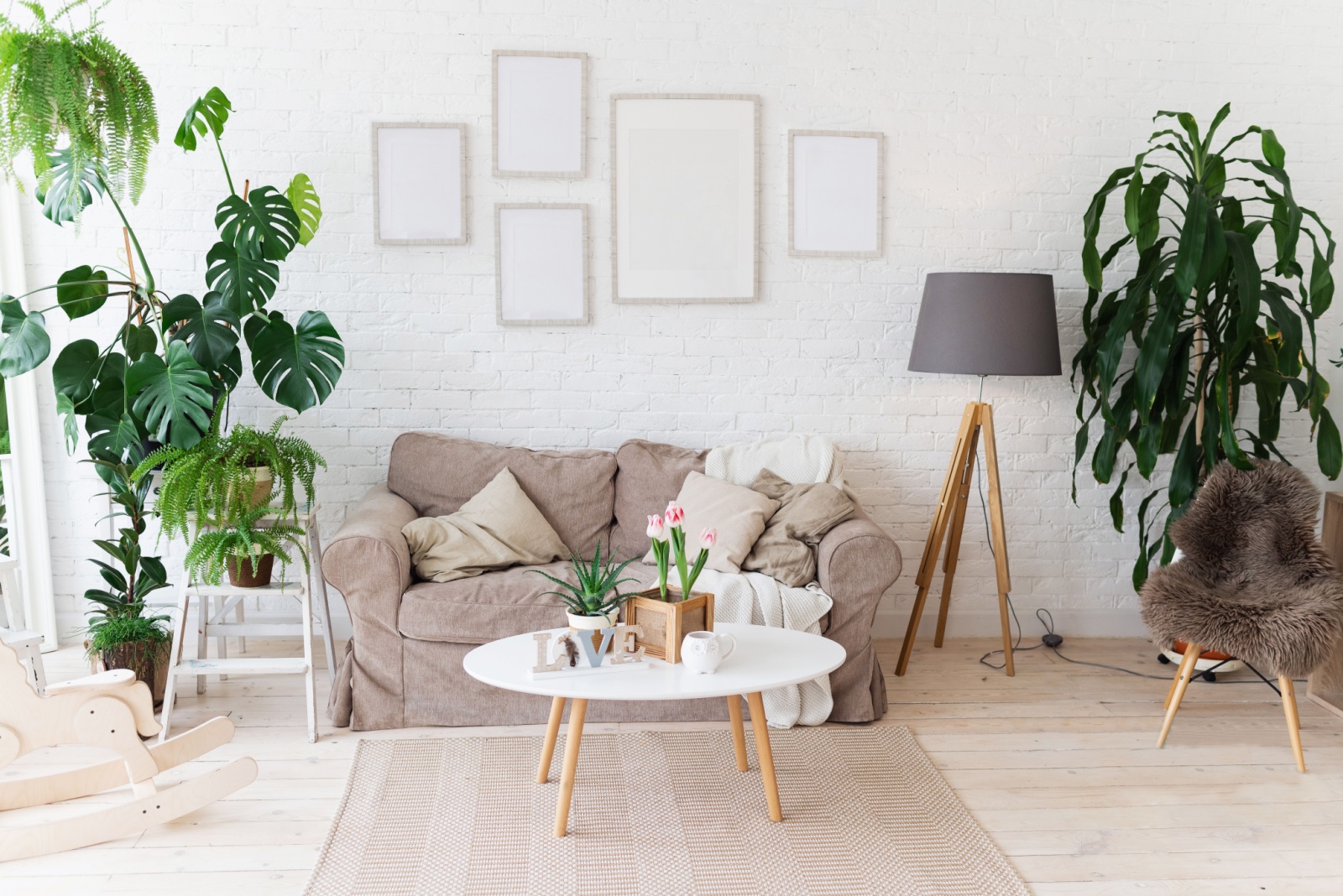 living room with a beige couch, white oval table, a lot pf plants