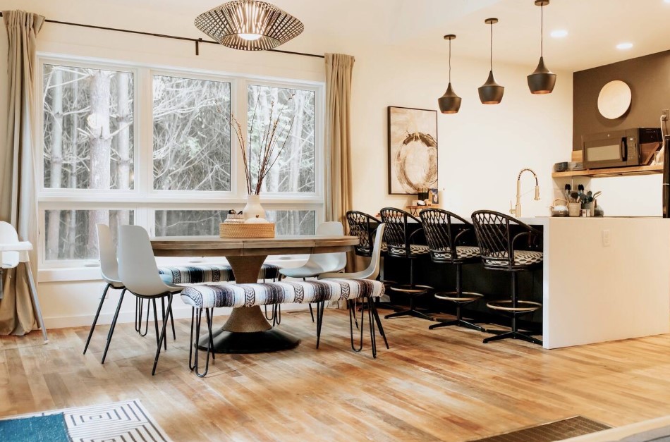 dining room and kitchen with big windows, island with black bar stools, dining table with white chairs