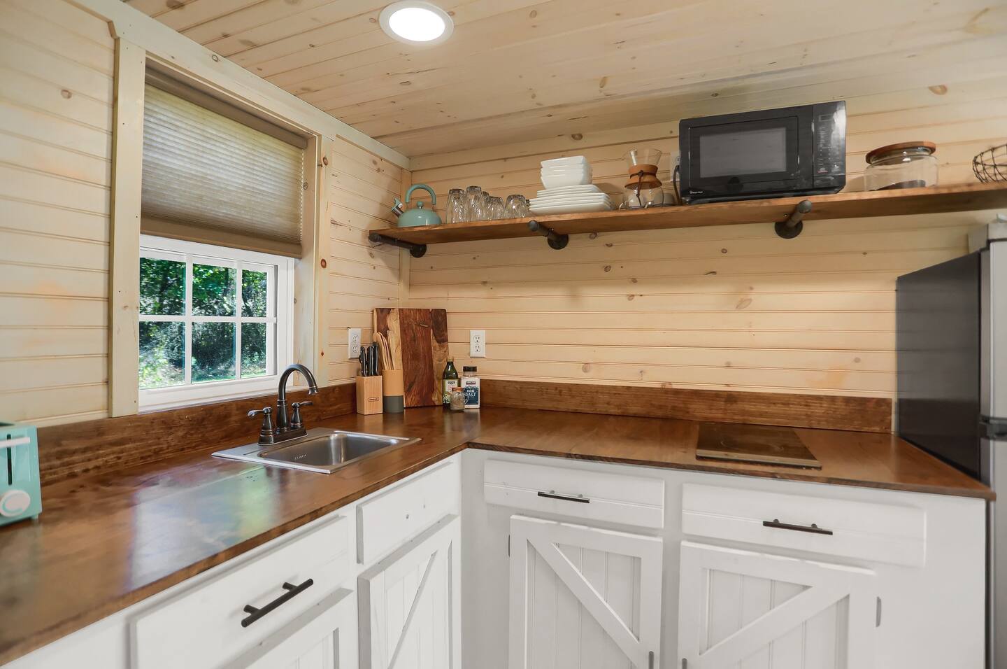 kitchen with an l-shaped wooden countertop and wooden walls and white cabinets