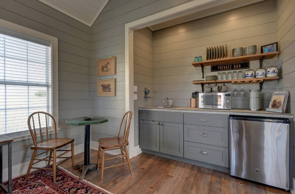 kitchen with gray cabinets, open shelves, tiny table and two wooden chairs