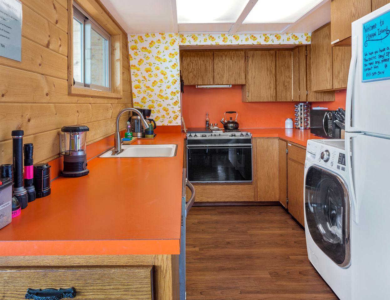 kitchen with an orange countertop, floral wallpaper, wooden cabinets