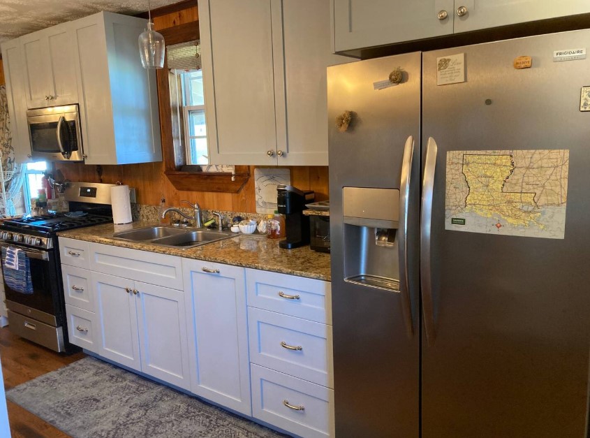 kitchen with white cabinets, wooden walls and a tiny window