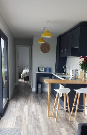 kitchen with black cabinets, yellow lamps, light brown table and two chairs