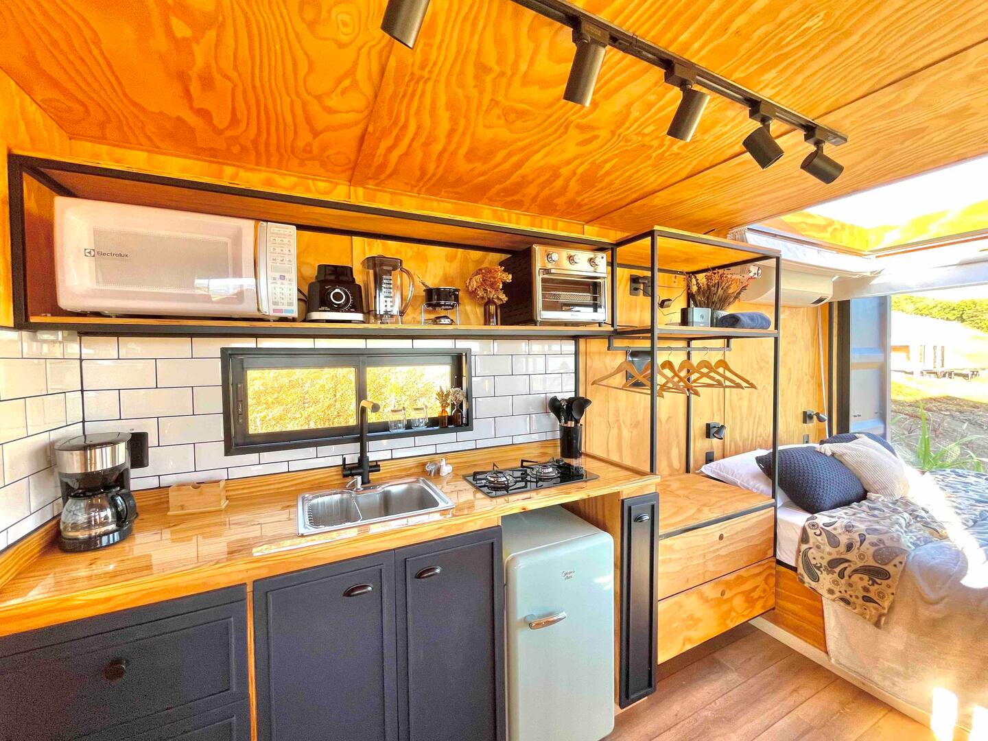 container home with black cabinets and wooden countertops, vintage fridge, open shelves, window above the sink