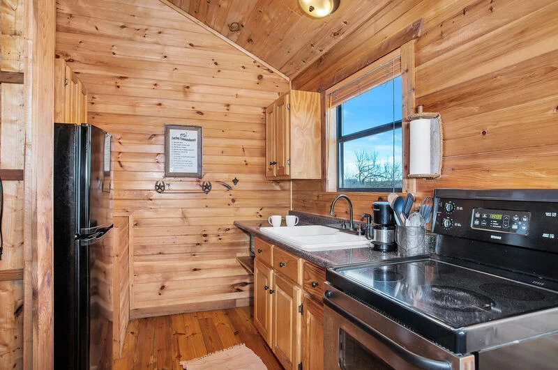 kitchen with wooden walls, wooden cabinets and a black fridge