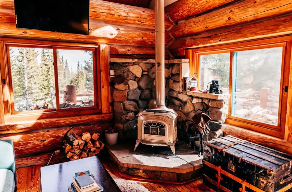 living room with a fireplace, log walls, big windows