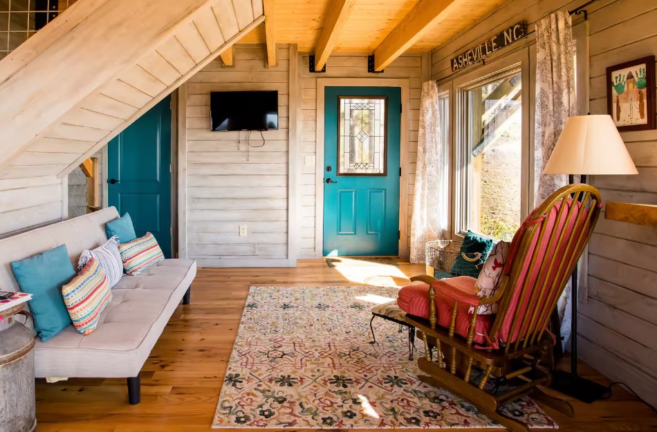 living room with a light beige couch, colorful pillows, chair, blue doors, big window