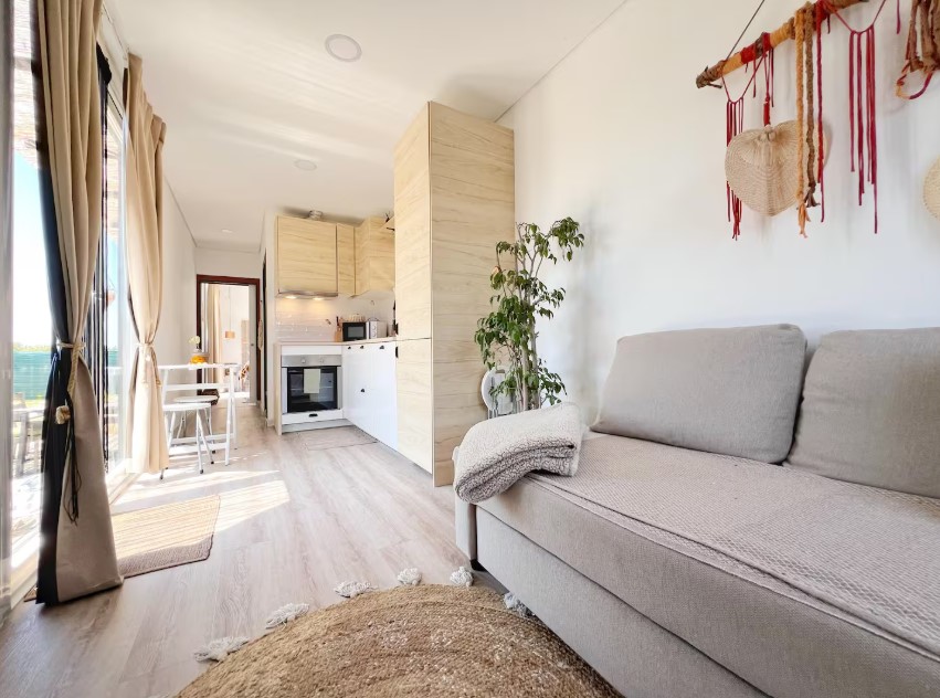 living room with a light beige couch, white walls, light brown carpet