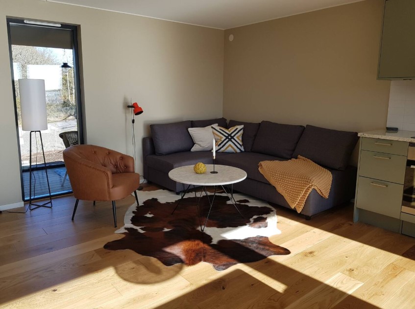 living room with an l-shaped couch, round white table, cowhide rug, caramel colored chair