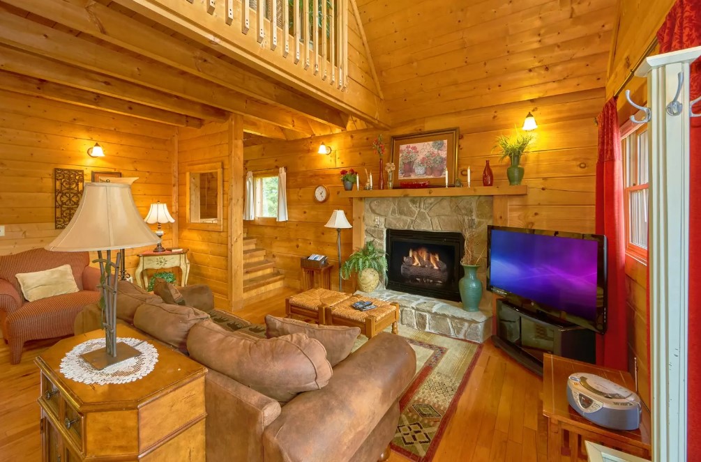 living room with a fireplace, flat screen tv, brown couch and sofa, wooden walls