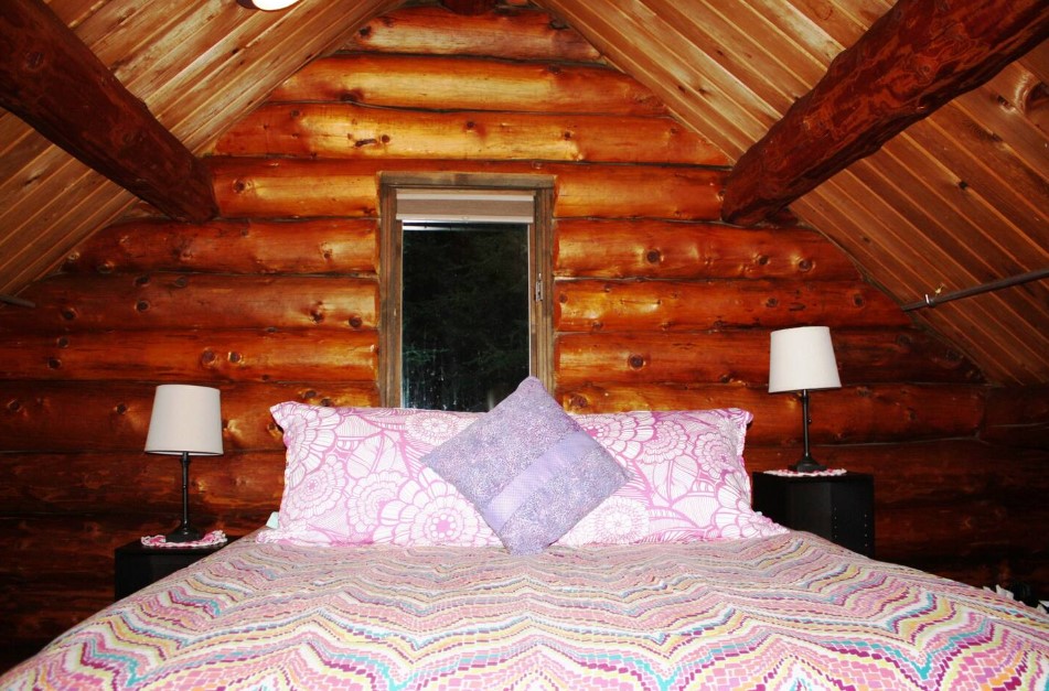 loft bedroom with a bed with colorful bed sheets and white lamps