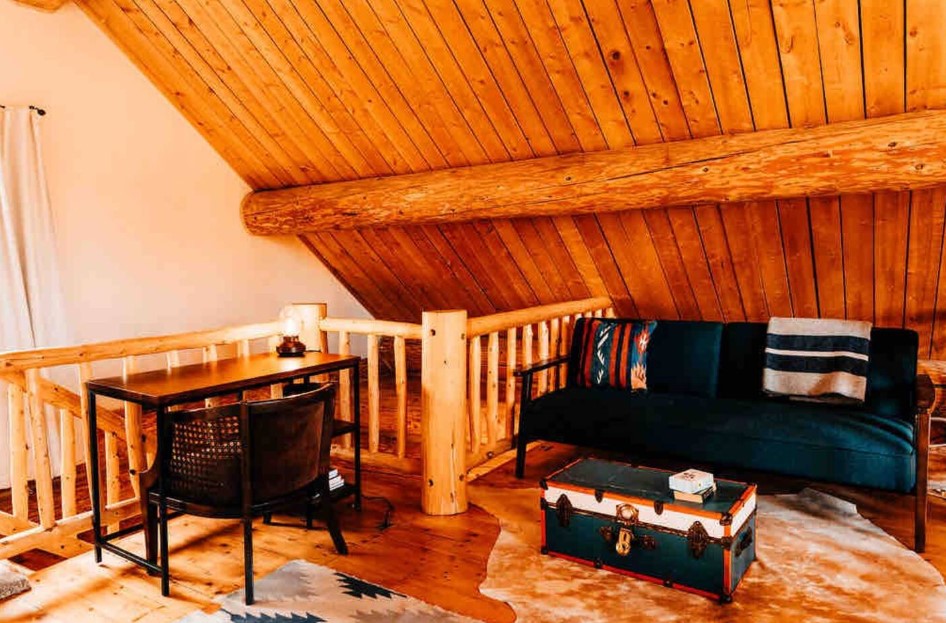 office area with a dark desk, navy blue couch, wooden walls