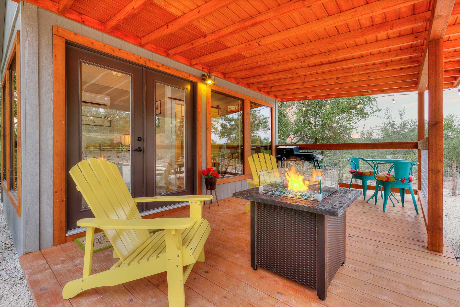 outdoor area with yellow chairs, fire table, a grill, blue table with two chairs