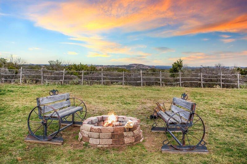 outdoors area of a cabin with a fire pit and two benches with wagon wheels