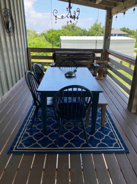 outdoors dining table with black chairs and a blue carpet