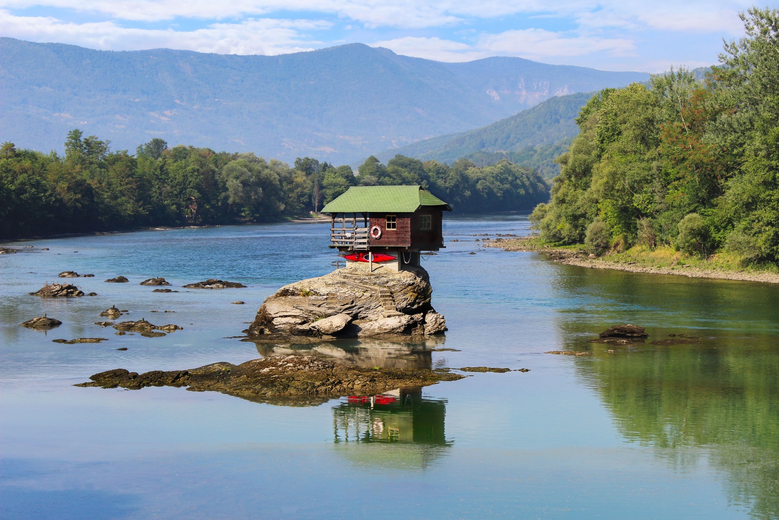 exterior of a tiny home on top of the rock in the middle of a river