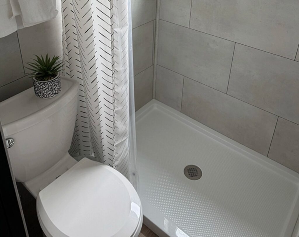 Tiny white bathroom with shower and a plant