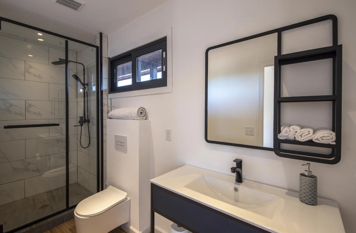 bathroom with black fixtures, glass shower, mirror with storage