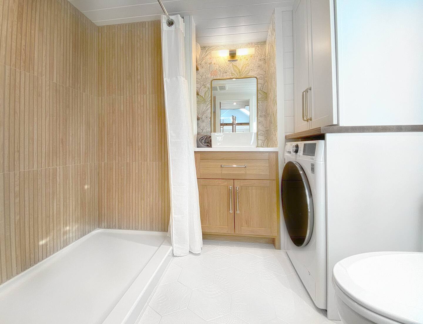 bathroom with textured floor tiles, brown cabinets, floral pattern behind the mirror