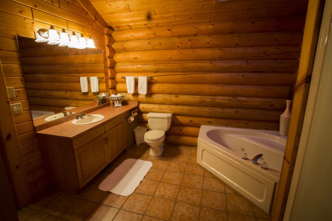 bathroom with soft dim lightning, white bath, wooden cabinet. big mirror