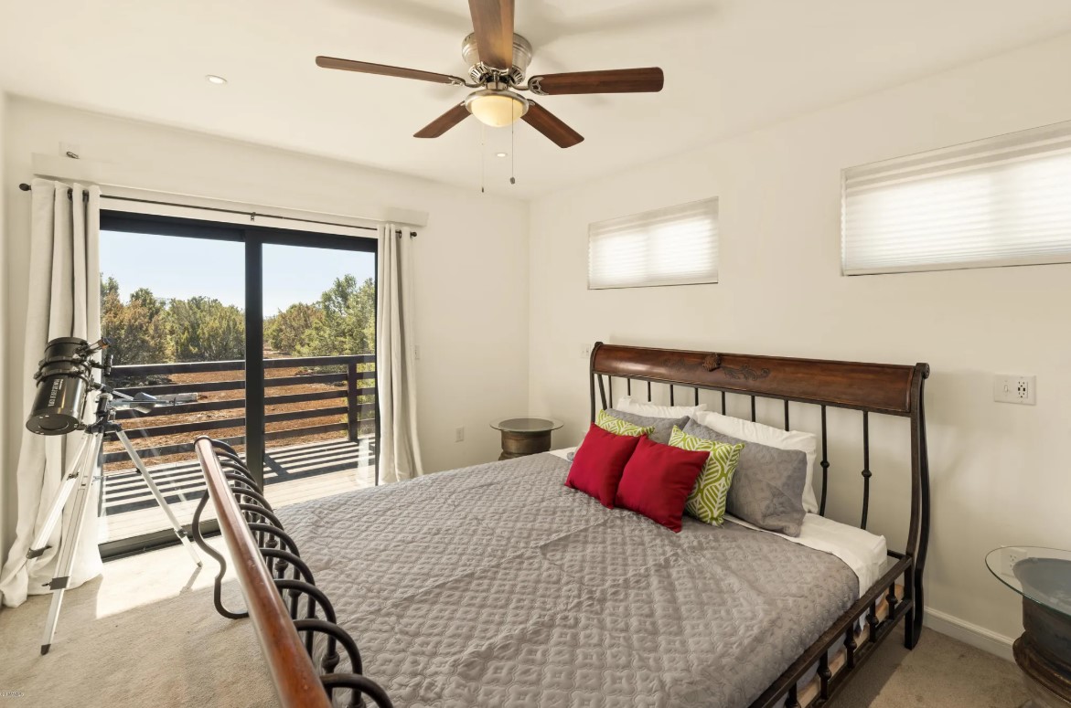 main bedroom with a bed, glass sliding doors, telescope, a fan on the ceiling