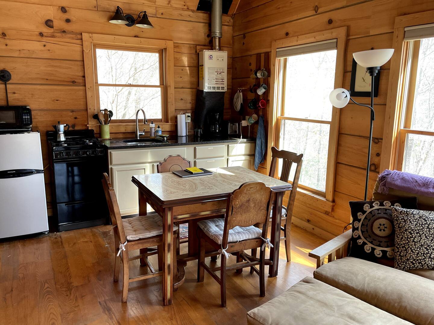 kitchen and dining room with creamy cabinets, mismatched chairs around the dining table, large windows