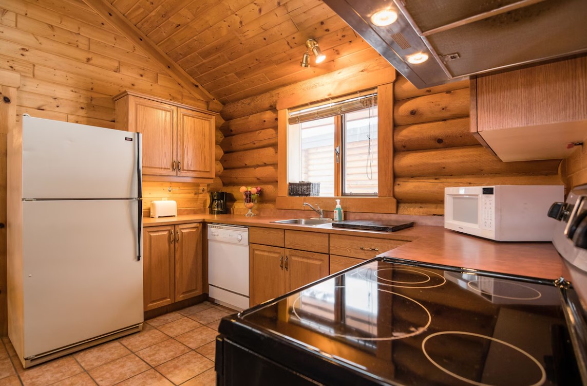 kitchen with wooden cabinets, log walls