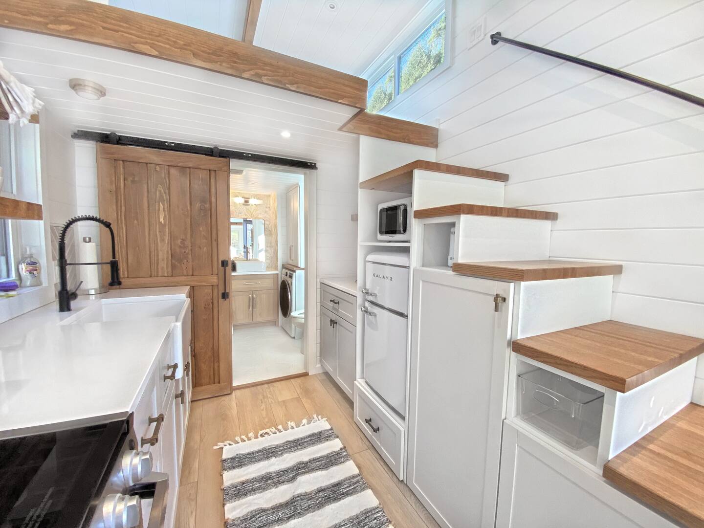 kitchen with white cabinets, white countertop, smart storage space, brown barn door