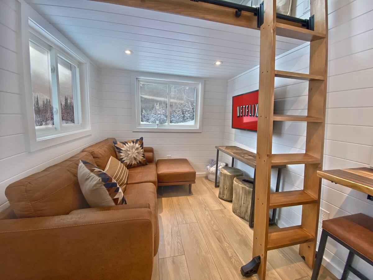 living room with a brown sectional, flat screen tv, brown table with log stools underneath