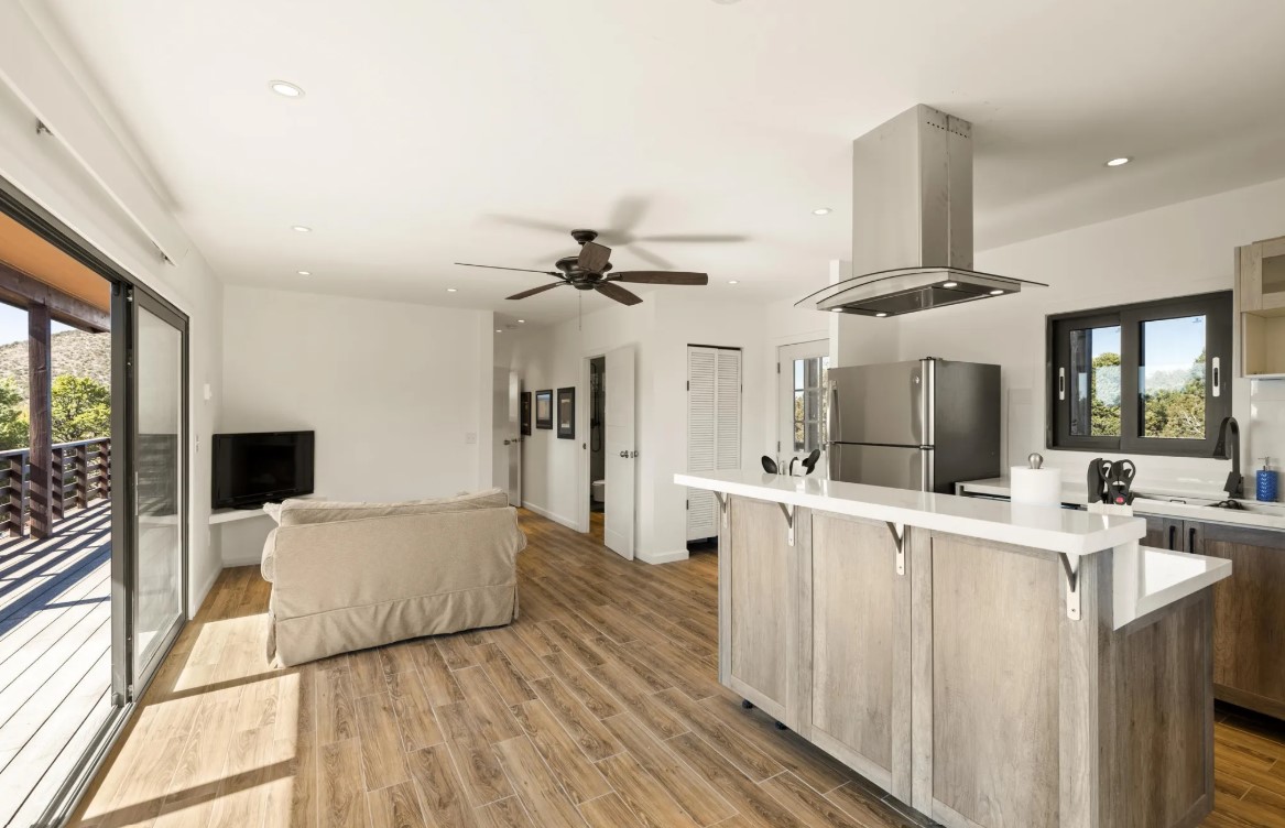 living room with a flat screen tv, beige couch, glass sliding doors, kitchen on the right