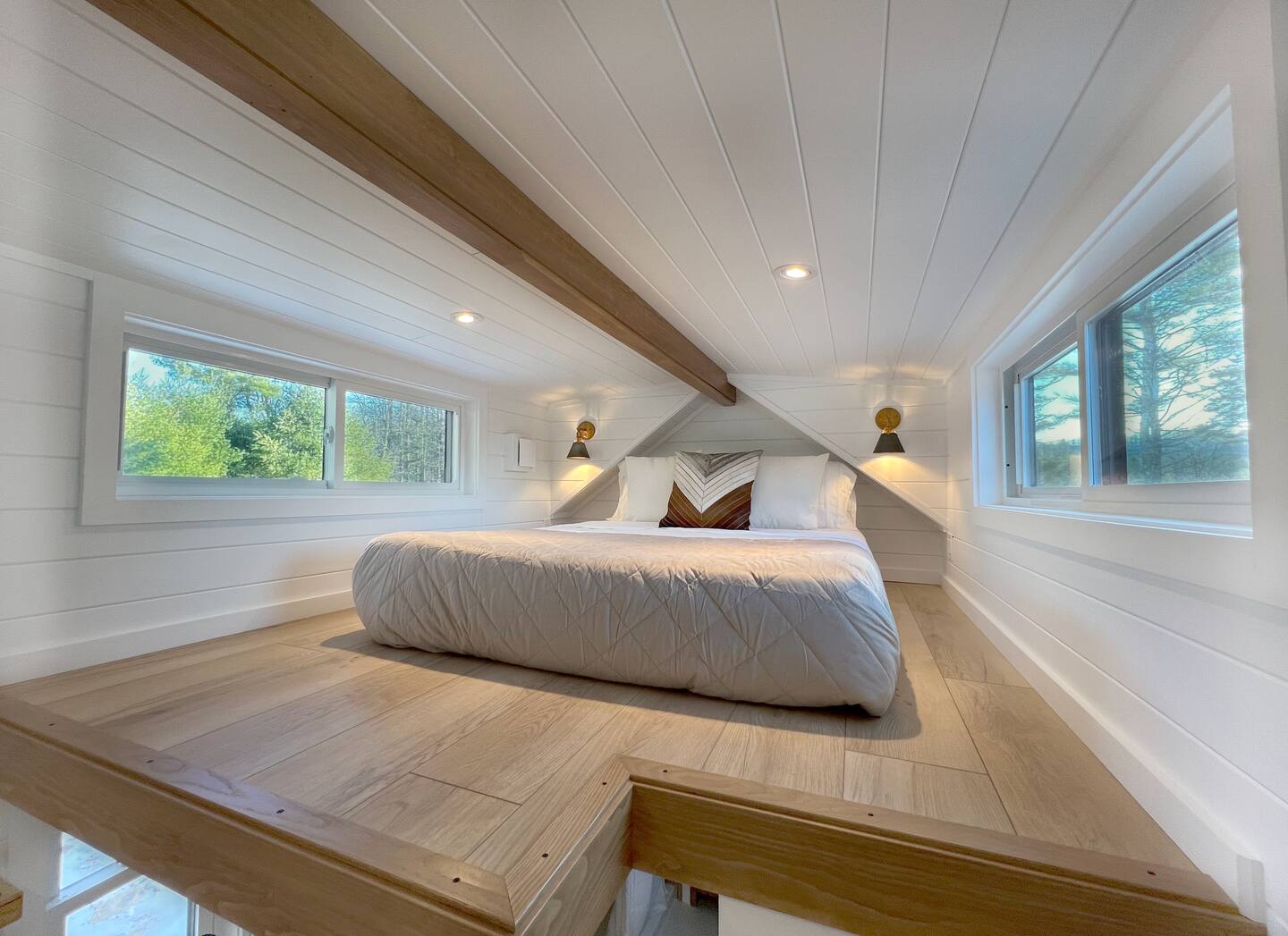 loft bedroom with a bed surrounded by windows and white walls