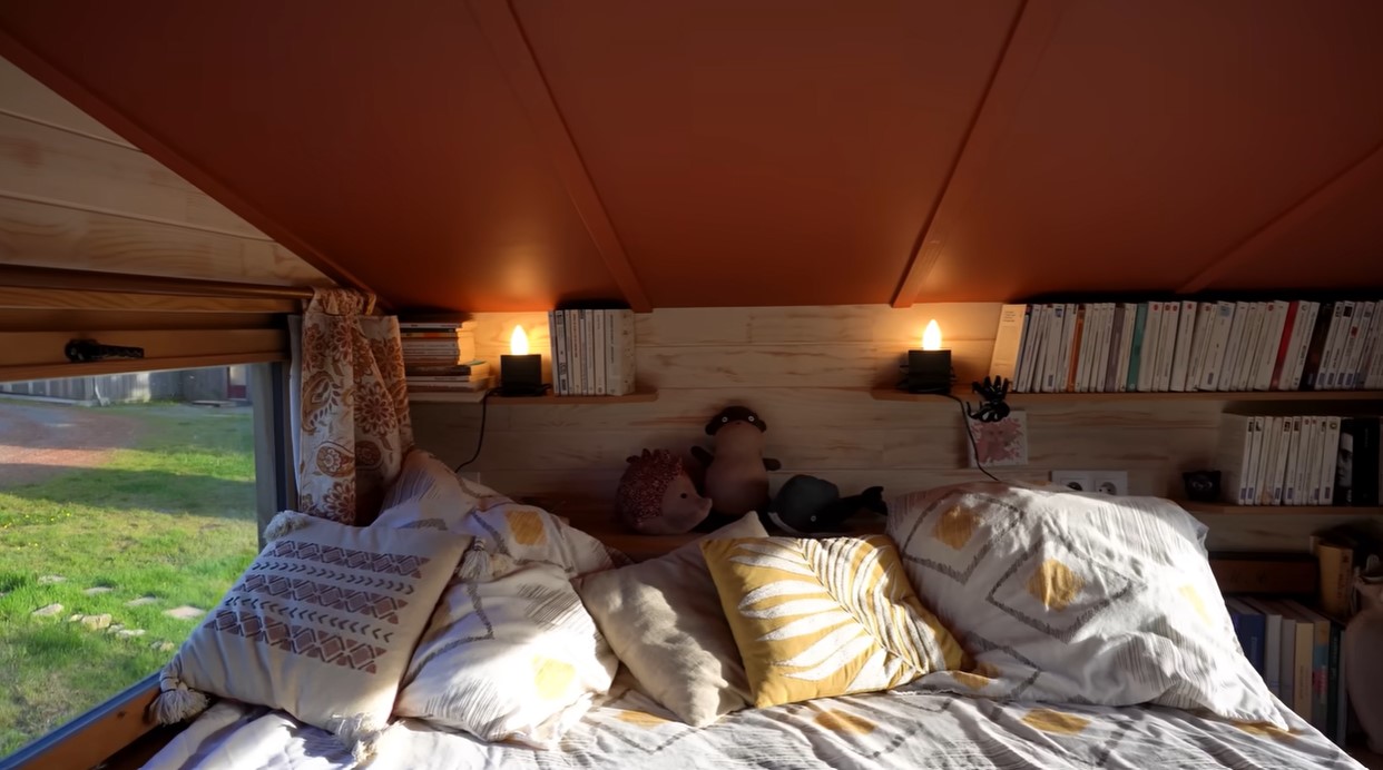 loft bedroom with a red ceiling, books on shelves, window next to the bed