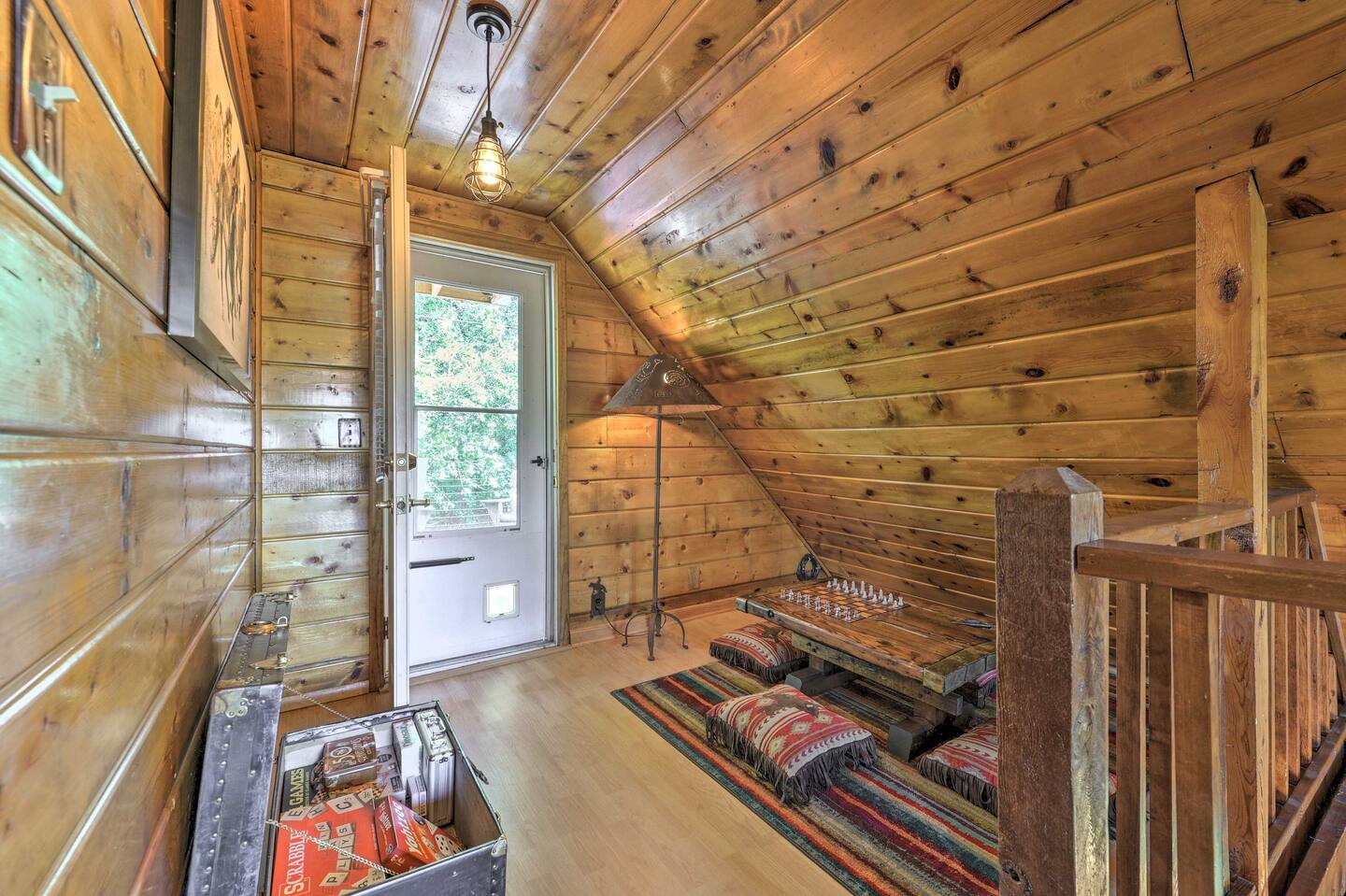 cabin loft with patterned pillows and a carpet and a trunk with games