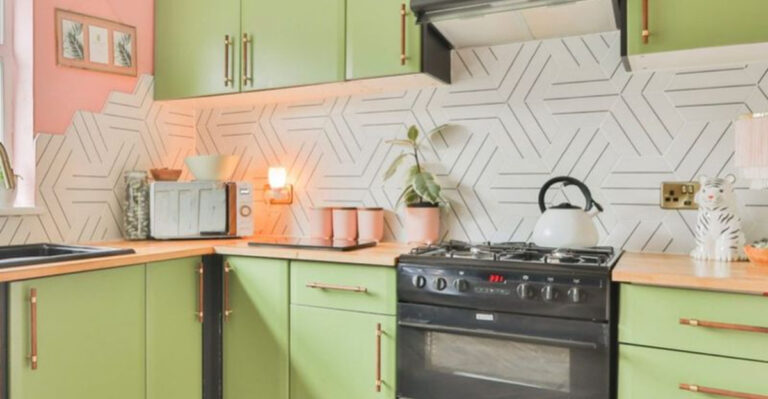 kitchen with light green cabinets and white tiles and pink walls